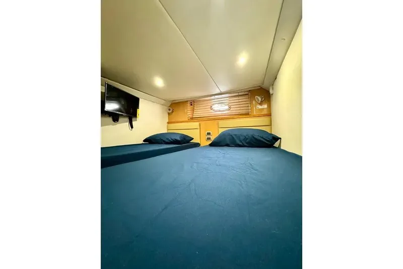 Slide: The Image of Cozy cabin interior of 2009 Four Winns V458 yacht with blue bedding and wall-mounted TV. - 12