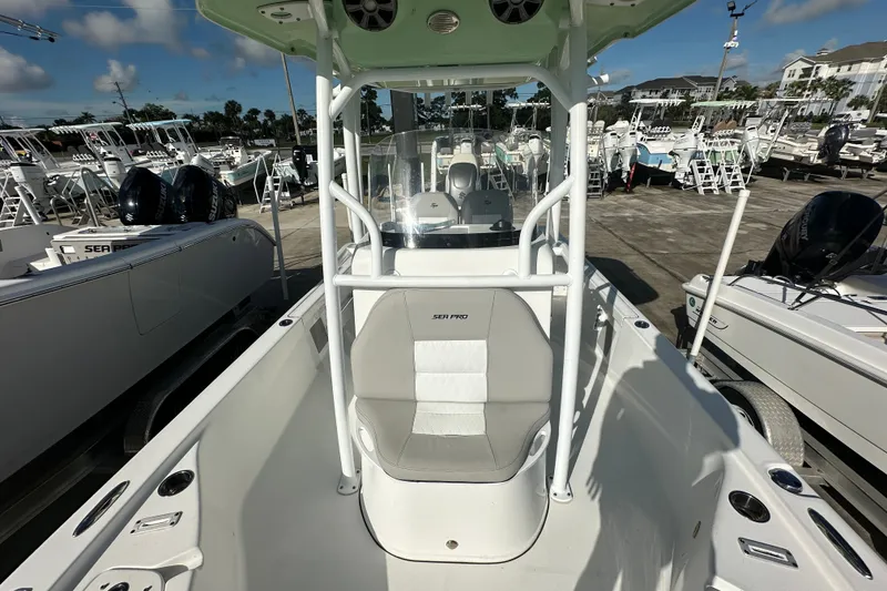 Slide: The Image of 2018 Sea Pro 248 Bay boat interior with seating and console, docked among other boats. - 15