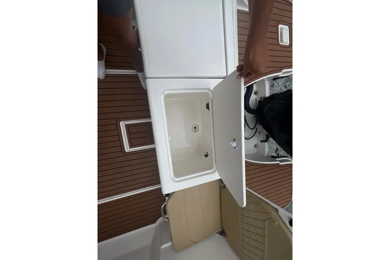 Slide: The Image of 2025 Bayliner Trophy T22CC boat interior with open storage compartment and teak flooring. - 22