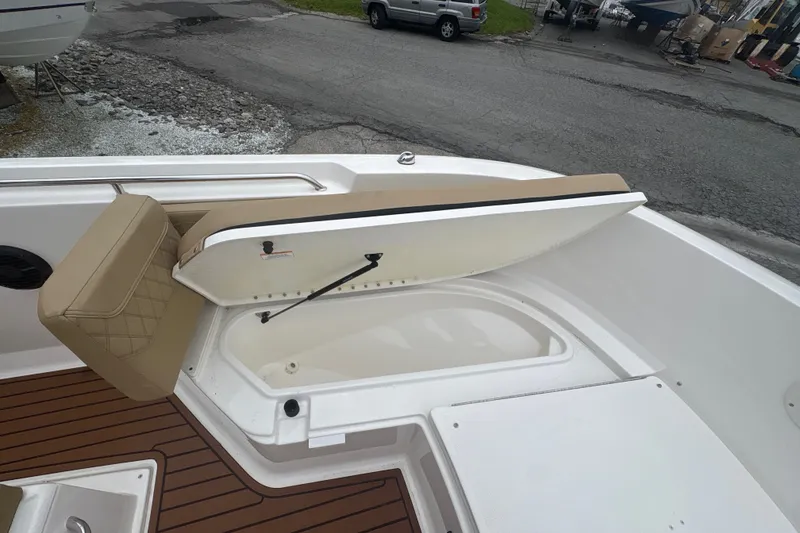 Slide: The Image of 2025 Bayliner Trophy T22CC boat with open storage compartment and cushioned seating. - 16