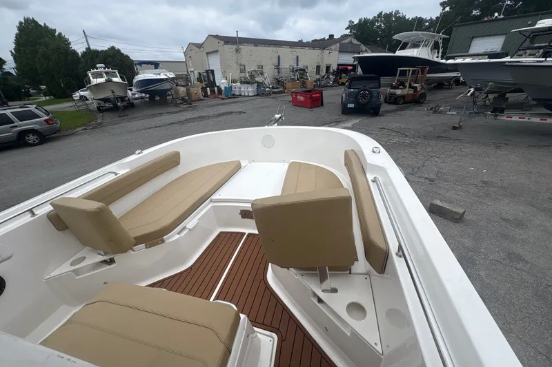 Slide: The Image of 2025 Bayliner Trophy T22CC boat with tan seating in a marina setting. - 14