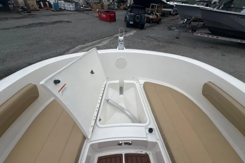 Slide: The Image of 2025 Bayliner Trophy T22CC boat interior with open storage compartment and beige seating. - 15