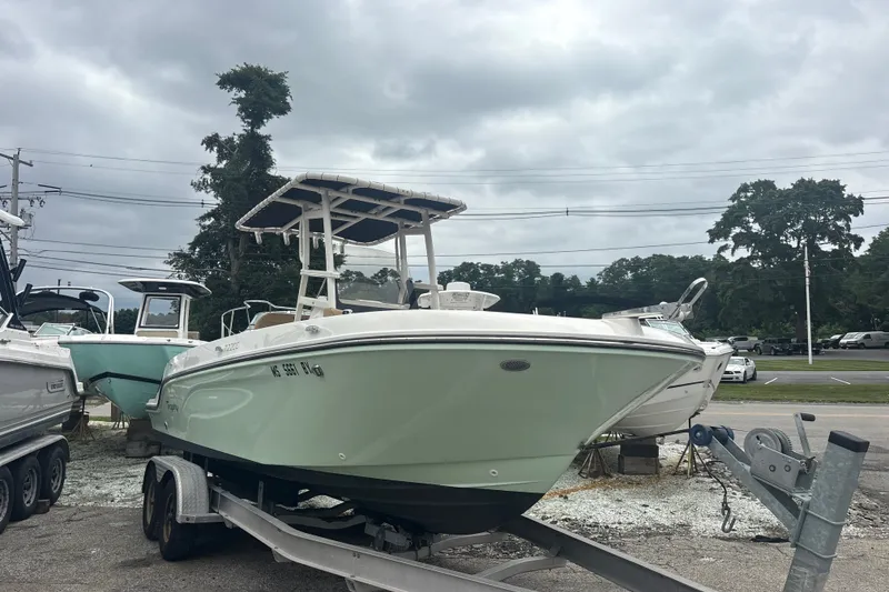 Slide: The Image of 2025 Bayliner Trophy T22CC boat on trailer, parked outdoors under cloudy sky. - 2
