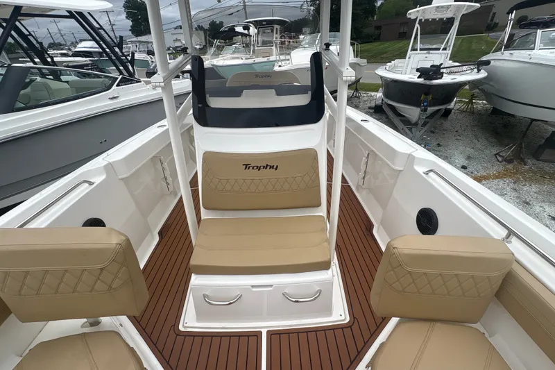 Slide: The Image of 2025 Bayliner Trophy T22CC boat interior with tan seating and wood-style flooring. - 19