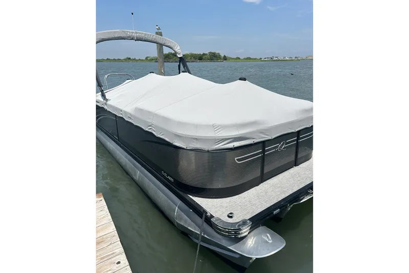 The Image of 2024 Qwest E822 Splash Pad pontoon boat docked with cover on, scenic water view. - 0