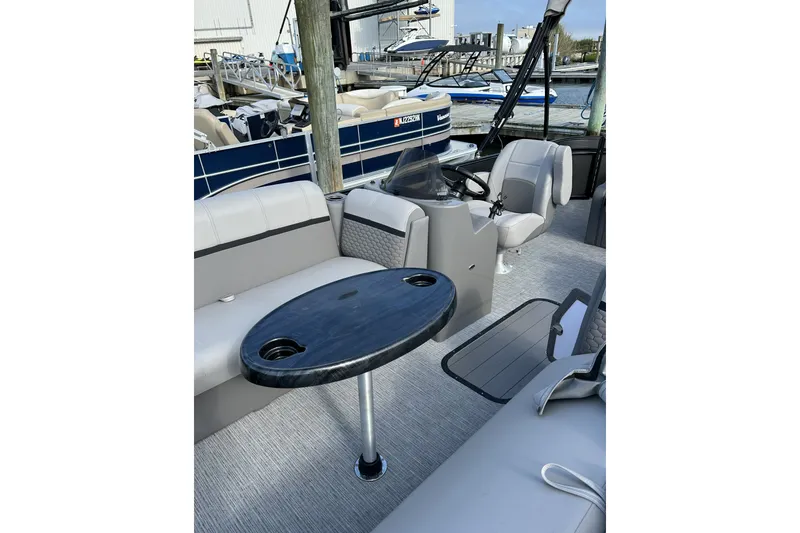 Slide: The Image of 2024 Qwest E822 Splash Pad boat interior with seating and table, docked at marina. - 4