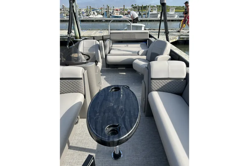 Slide: The Image of 2024 Qwest E822 Splash Pad pontoon boat interior with plush seating and sleek table design. - 3