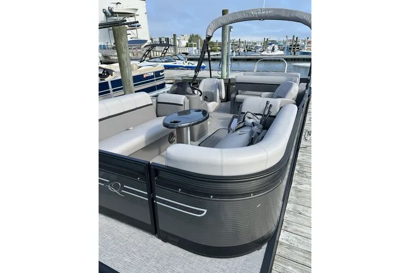 Slide: The Image of 2024 Qwest E822 Splash Pad pontoon boat with spacious seating at a marina dock. - 1