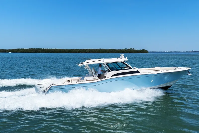 Slide: The Image of 2023 Grady-White Canyon 456 boat cruising on open water under clear blue sky. - 2