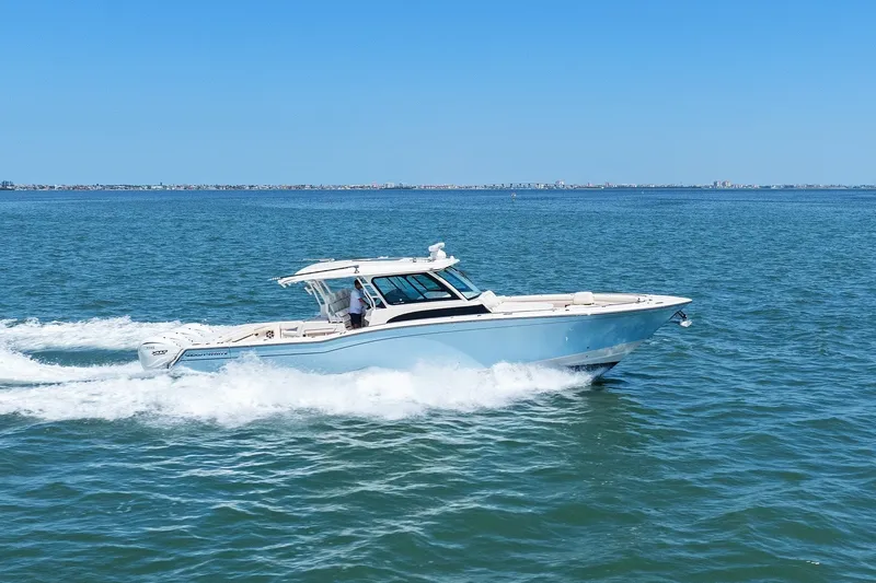 The Image of 2023 Grady-White Canyon 456 cruising on open water under clear blue skies. - 0