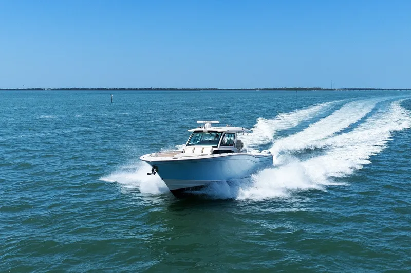 Slide: The Image of 2023 Grady-White Canyon 456 cruising on open water under clear blue skies. - 16