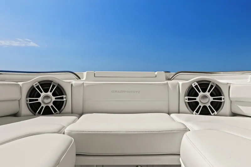 Slide: The Image of 2023 Grady-White Canyon 456 boat interior with speakers, white seating, and blue sky background. - 63