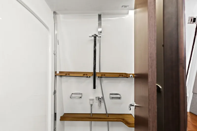 Slide: The Image of Shower area in 2023 Grady-White Canyon 456 boat, featuring modern fixtures and wooden shelves. - 58