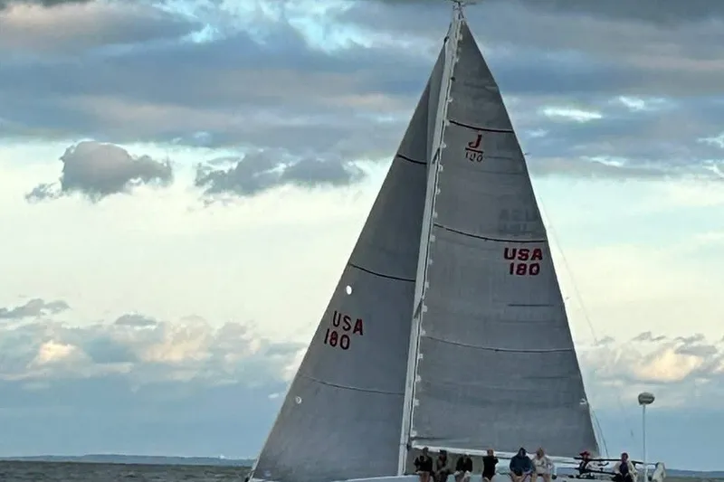 Slide: The Image of 2002 J Boats J/120 sailboat with crew, sailing under cloudy skies. - 3