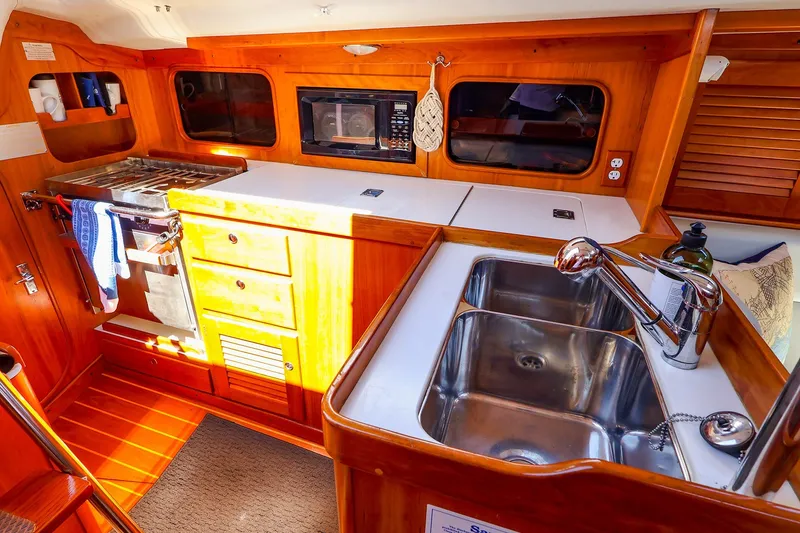 Slide: The Image of Cozy galley kitchen in 2002 J Boats J/120 yacht with stove, sink, and wooden cabinetry. - 42