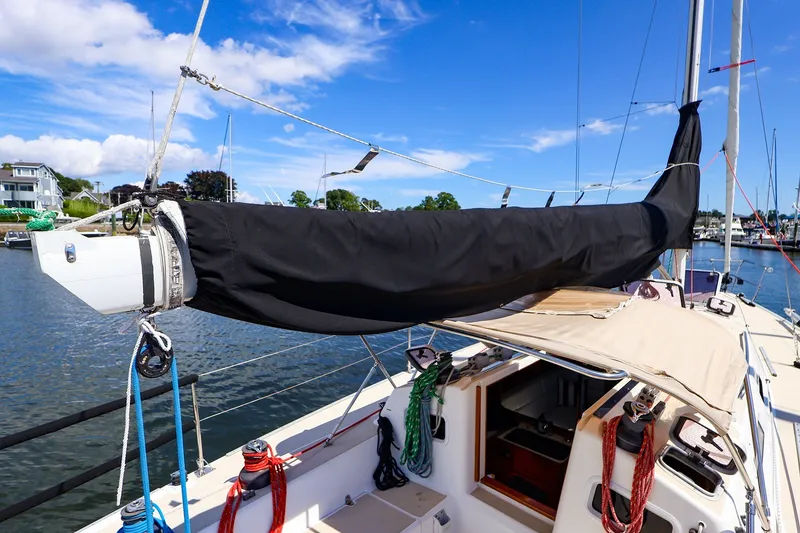 Slide: The Image of 2002 J Boats J/120 sailboat with covered boom, docked in a marina under blue skies. - 30