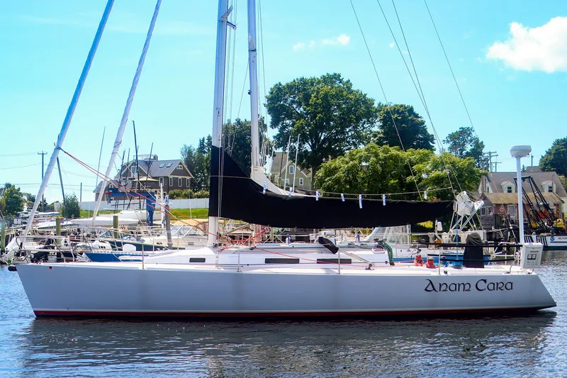 Slide: The Image of 2002 J Boats J/120 sailboat docked in a marina, surrounded by trees and buildings. - 2