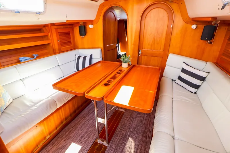 Slide: The Image of Interior of 2002 J Boats J/120 sailboat with wooden table and cushioned seating. - 50