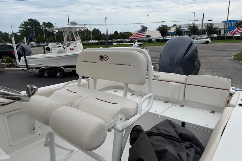 Slide: The Image of 2022 Sea Hunt Ultra 219 boat interior with seating and motor, parked outdoors. - 8