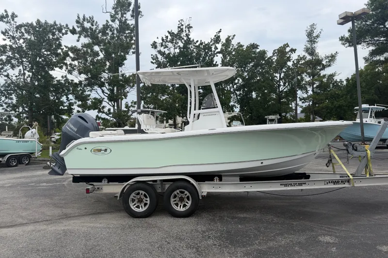 Slide: The Image of 2022 Sea Hunt Ultra 219 boat on trailer, parked outdoors with trees in background. - 2