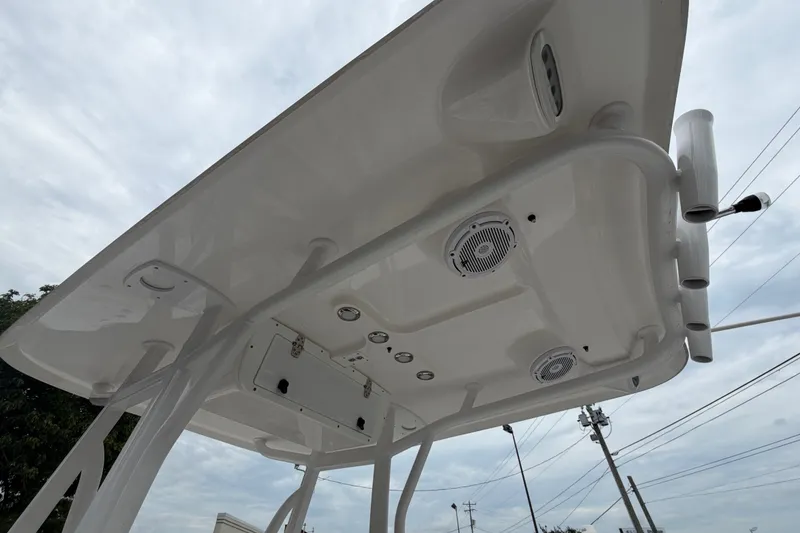 Slide: The Image of 2022 Sea Hunt Ultra 219 boat's T-top with speakers and rod holders under cloudy sky. - 10