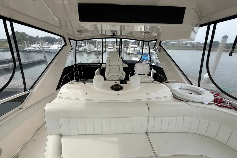 Slide: The Image of 1997 Sea Ray 550 Sedan Bridge yacht interior with white seating and marina view. - 13
