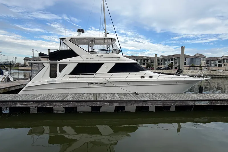 Slide: The Image of 1997 Sea Ray 550 Sedan Bridge yacht docked at marina under blue sky. - 2