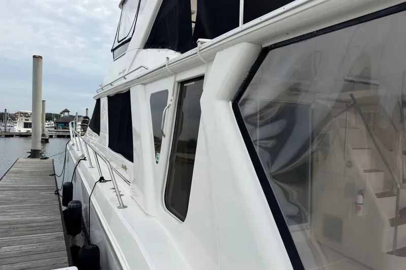 Slide: The Image of 1997 Sea Ray 550 Sedan Bridge yacht docked at marina, showcasing sleek design and windows. - 10