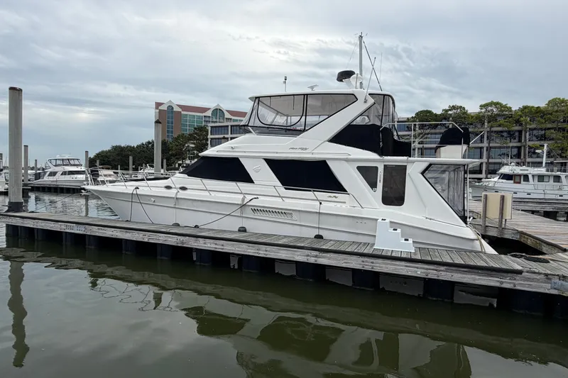 Slide: The Image of 1997 Sea Ray 550 Sedan Bridge yacht docked at marina under cloudy sky. - 4