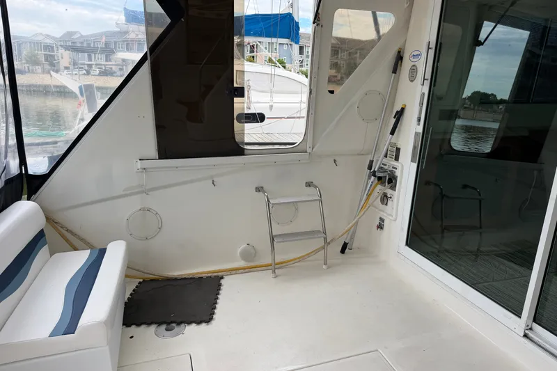 Slide: The Image of 1997 Sea Ray 550 Sedan Bridge interior with seating, ladder, and marina view. - 7