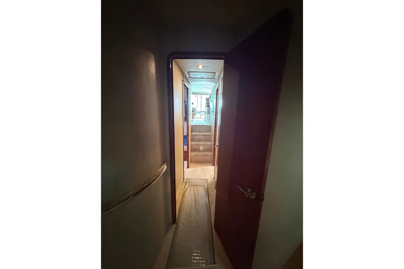 Slide: The Image of Interior hallway of 1997 Sea Ray 550 Sedan Bridge yacht, featuring carpeted flooring and wooden doors. - 39