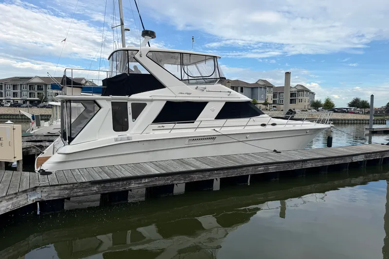 Slide: The Image of 1997 Sea Ray 550 Sedan Bridge yacht docked at marina, clear sky background. - 1