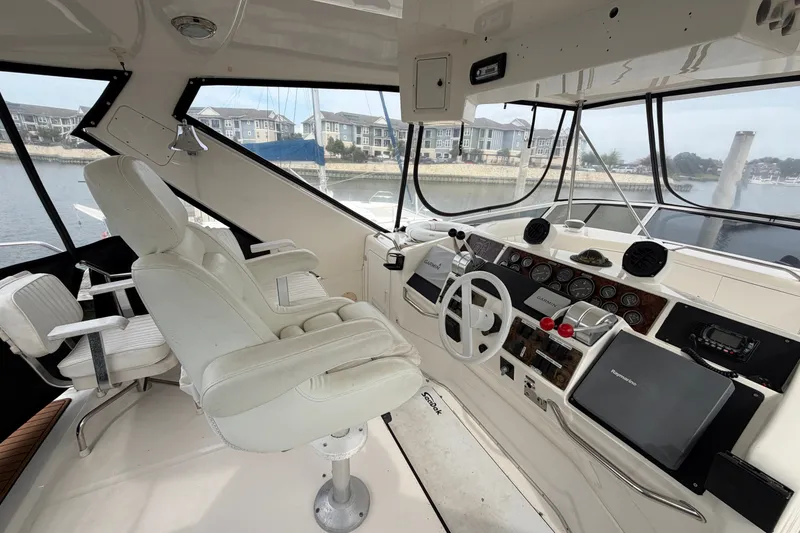Slide: The Image of 1997 Sea Ray 550 Sedan Bridge helm with white captain's chair and navigation instruments. - 11