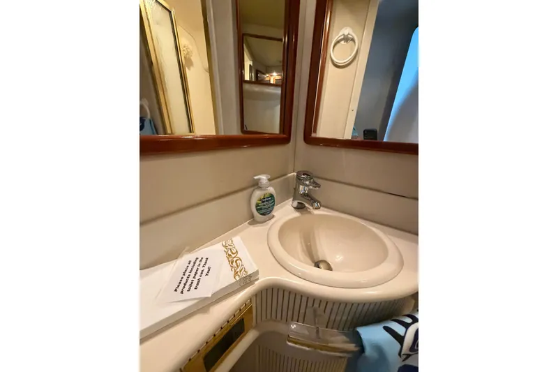 Slide: The Image of Bathroom sink area on 1997 Sea Ray 550 Sedan Bridge yacht, featuring mirror and soap dispenser. - 35