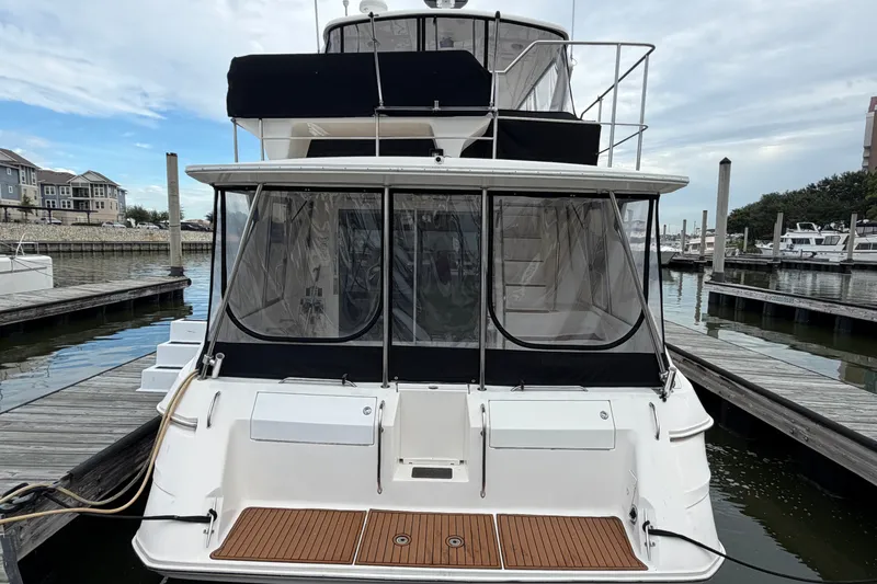 Slide: The Image of 1997 Sea Ray 550 Sedan Bridge yacht docked at marina, rear view with enclosed deck. - 3