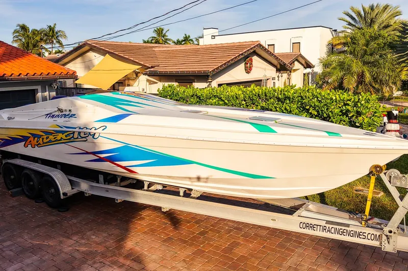 The Image of 2000 Active Thunder 32 speedboat on trailer, vibrant graphics, parked in residential driveway. - 0