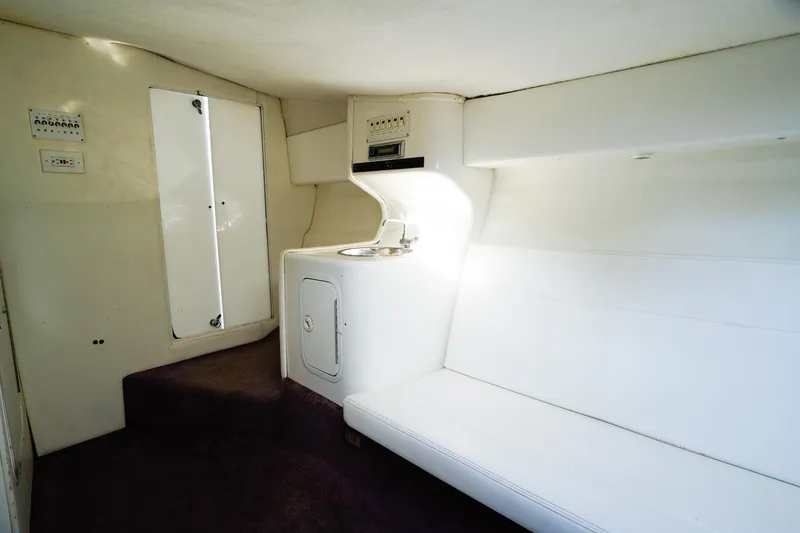 Slide: The Image of Interior of 2000 Active Thunder 32 boat, featuring white seating and compact kitchenette. - 18