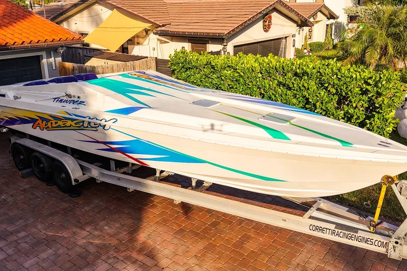 Slide: The Image of 2000 Active Thunder 32 boat on trailer, vibrant graphics, parked in residential driveway. - 23