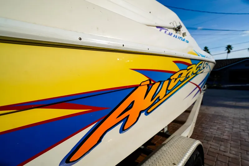 Slide: The Image of 2000 Active Thunder 32 boat with vibrant yellow and blue graphics on trailer. - 19