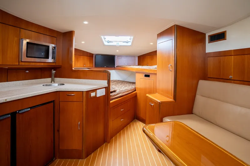 Slide: The Image of Luxurious 2011 Cabo 36 Express yacht interior with kitchenette, seating, and cozy sleeping area. - 37