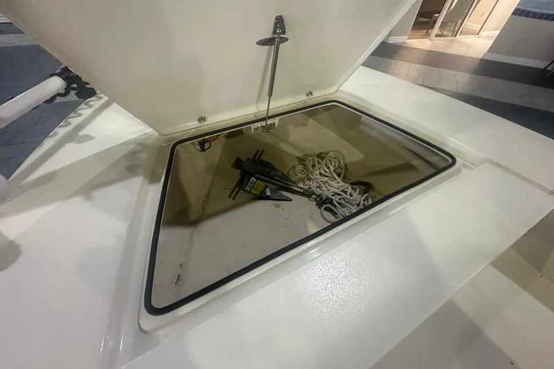 Slide: The Image of Open storage compartment on 2024 Hewes Redfisher 16 boat, containing rope and tools. - 7