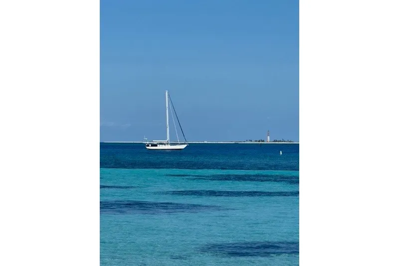 Slide: The Image of Sailboat on clear blue ocean, Reliance 44 model, 2011, with distant lighthouse. - 60