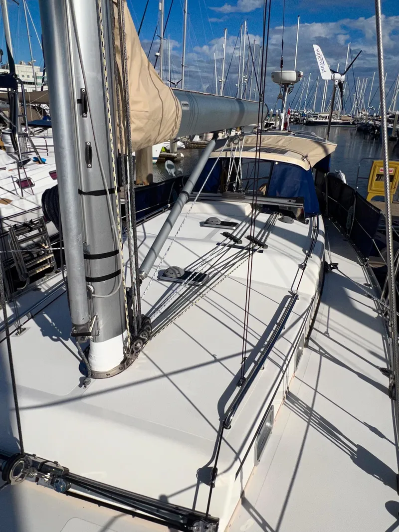 Slide: The Image of Das Bild zeigt ein Segelboot mit einem weißen Deck und einem großen Mast. Es liegt in einem Hafen. - 47