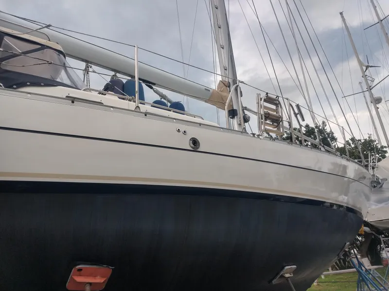 Slide: The Image of Segelboot mit weißem Rumpf und blauen Akzenten, an Land aufgebockt, mit grauem Himmel im Hintergrund. - 55