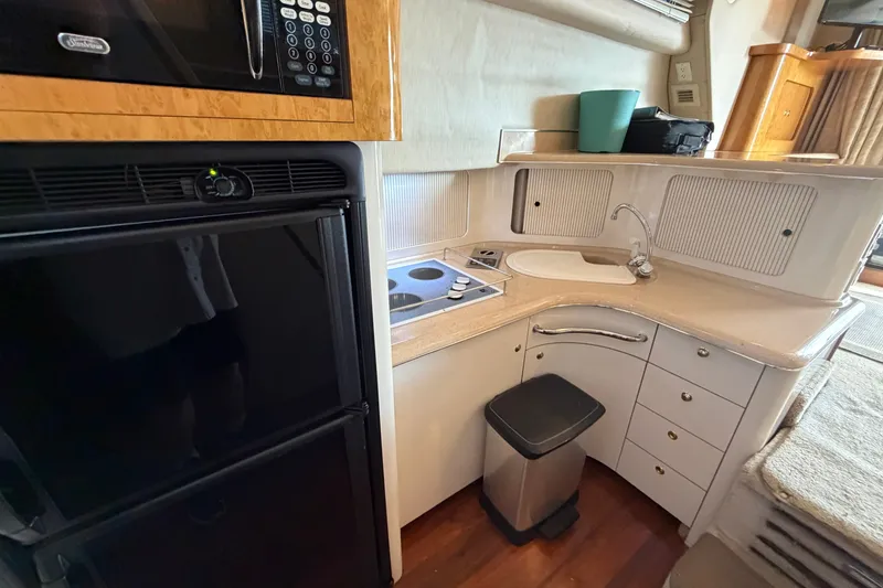 Slide: The Image of 1997 Sea Ray 400 Sedan Bridge kitchen with microwave, stove, sink, and refrigerator. - 16