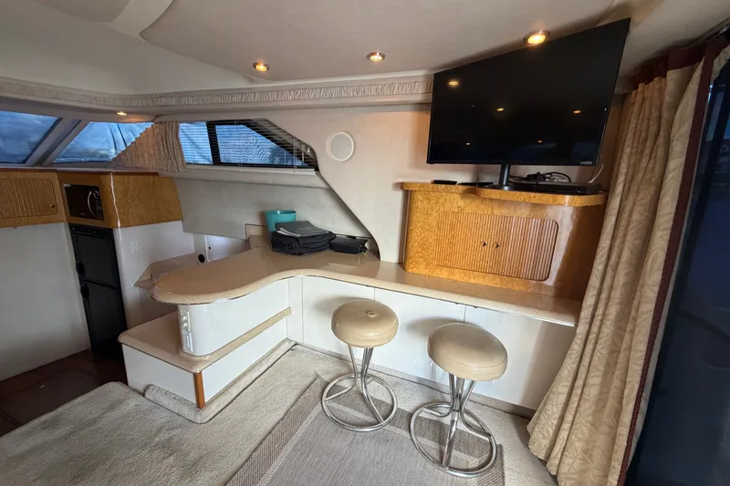 Slide: The Image of Interior of 1997 Sea Ray 400 Sedan Bridge with TV, bar stools, and counter. - 11