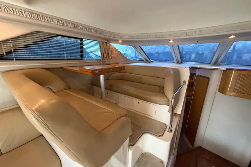 Slide: The Image of Interior of 1997 Sea Ray 400 Sedan Bridge with beige seating and wooden table. - 13
