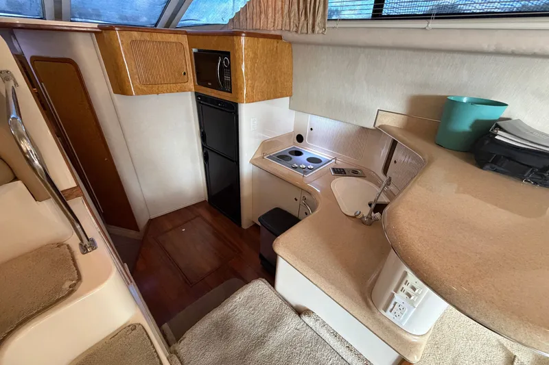 Slide: The Image of 1997 Sea Ray 400 Sedan Bridge yacht interior kitchen with stove, sink, and microwave. - 14