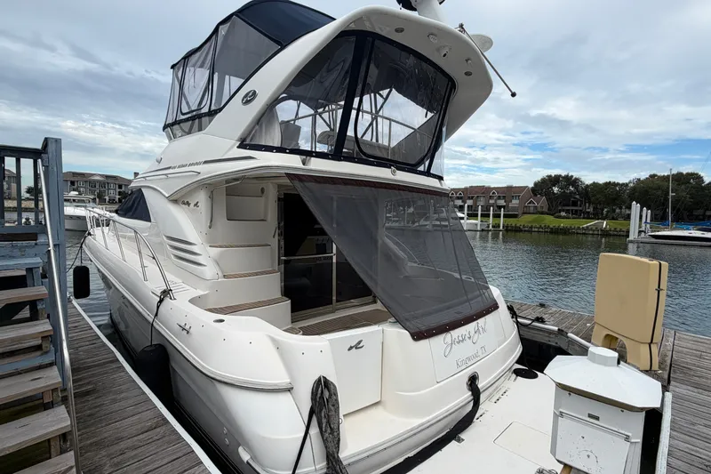 Slide: The Image of 1997 Sea Ray 400 Sedan Bridge yacht docked at marina, featuring spacious upper deck. - 1