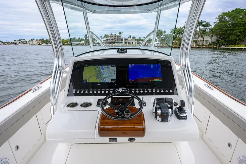 Slide: The Image of 2022 Valhalla V-37 boat dashboard with navigation screens and controls on a calm waterway. - 37